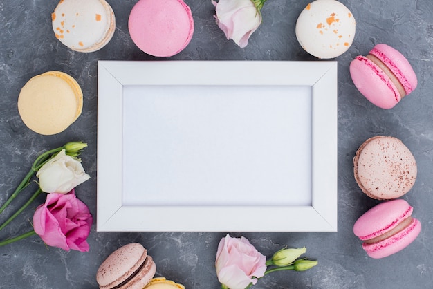 Photo gratuite vue de dessus du cadre avec de délicieux macarons et roses