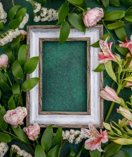 Vue de dessus du cadre gris avec des fleurs rose clair sur une surface verte