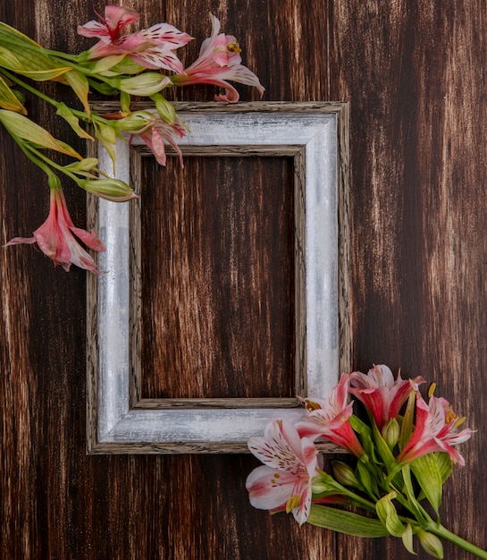 Vue de dessus du cadre gris avec des lys roses sur une surface en bois