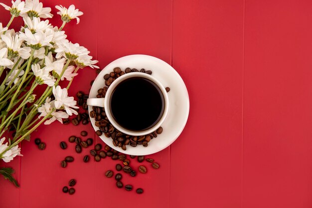 Vue de dessus du café sur une tasse blanche avec des fleurs sur fond rouge avec espace copie