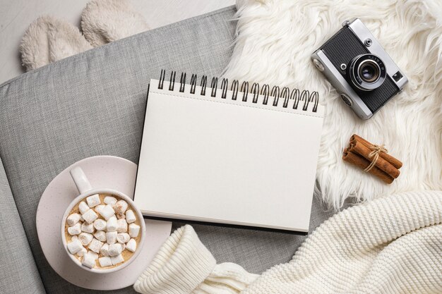 Vue de dessus du cahier avec appareil photo et tasse de chocolat chaud avec des guimauves