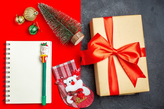 Vue de dessus du cahier de chaussette d'arbre de Noël beau cadeau avec stylo sur fond rouge et noir