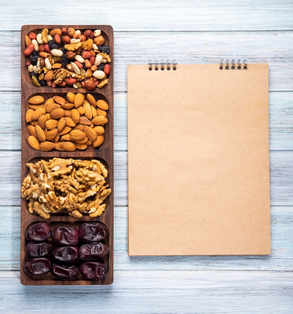 Vue de dessus du carnet de croquis et mélange de noix avec des amandes de noix et des dattes séchées