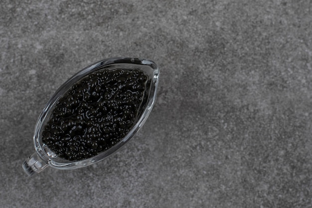 Photo gratuite vue de dessus du caviar noir. caviar dans un bol en verre sur une table grise.