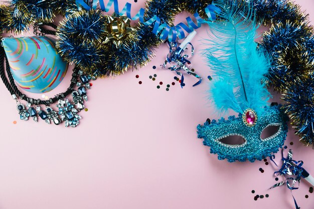 Vue de dessus du chapeau de fête; clinquant; collier avec confettis et mascarade bleue masque de plume de carnaval