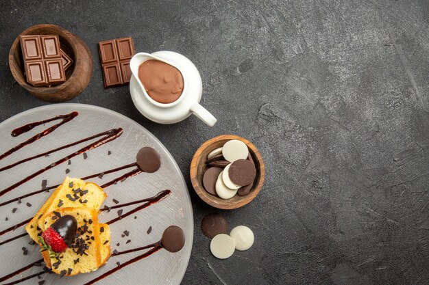 Vue de dessus du chocolat sur la table des bols de chocolat et de la crème au chocolat à côté de l'assiette de gâteau avec des fraises et du chocolat sur la table