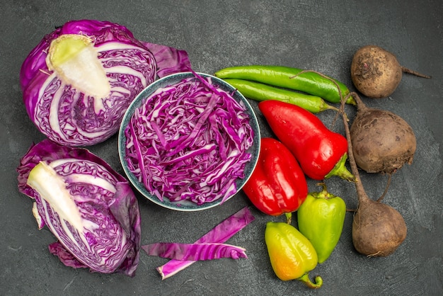 Vue de dessus du chou rouge tranché avec des légumes frais sur fond sombre