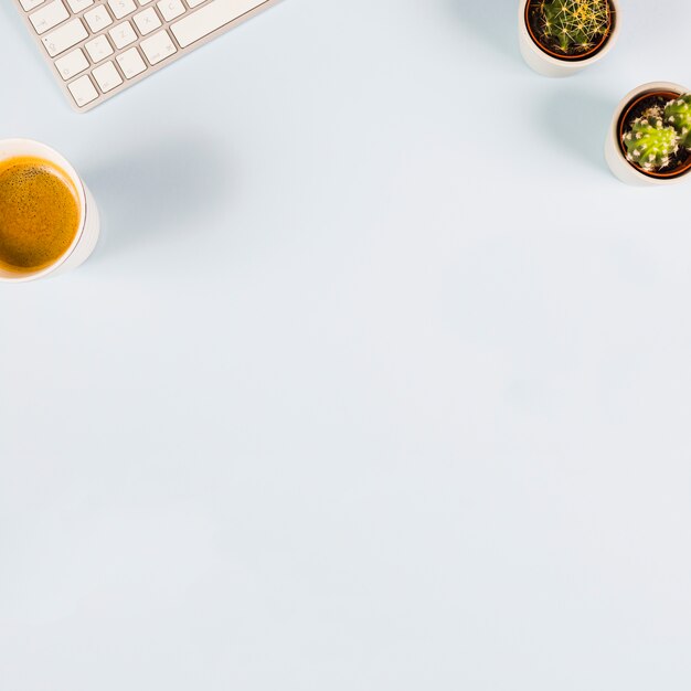 Une vue de dessus du clavier; tasse de café et de cactus sur fond blanc