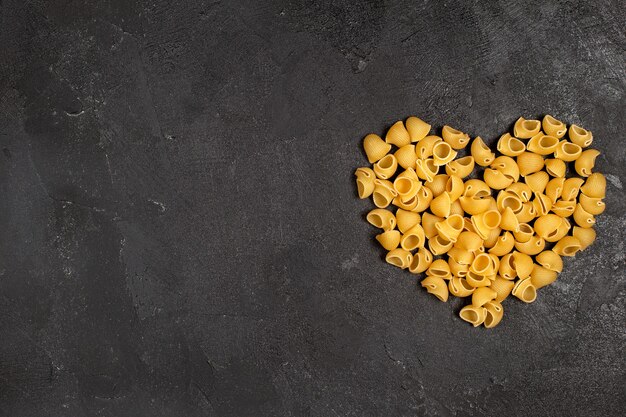 Vue de dessus du coeur de pâtes italiennes crues en forme sur la surface sombre