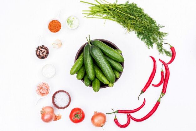 Vue de dessus du concombre dans un bol avec du piment à l'ail et des épices sur horizontal blanc