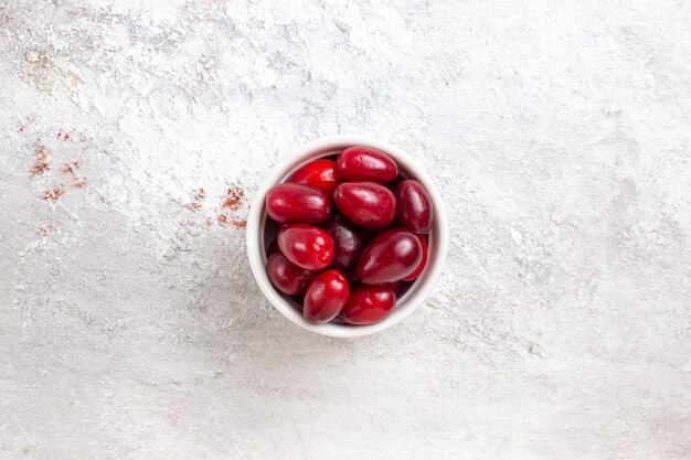 Vue de dessus du cornouiller rouge à l'intérieur de la petite assiette sur la surface blanche de la plante d'arbre fruit berry