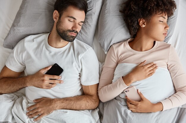 Vue de dessus du couple familial de race mixte accro ont un sommeil profond