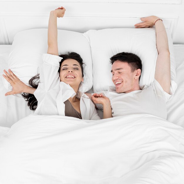 Vue de dessus du couple souriant se réveiller le matin