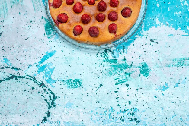 Vue de dessus du délicieux gâteau aux fraises en forme ronde avec des fruits sur le dessus sur bleu vif, pâte à gâteau biscuit sucré fruit berry