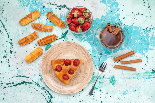 Vue de dessus du délicieux gâteau aux fraises en tranches délicieux gâteau avec du thé à la cannelle et des bracelets sur bleu vif, pâte de berry cake sweet bake