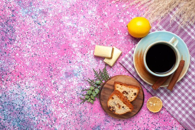 Vue de dessus du délicieux gâteau en tranches avec une tasse de thé à la cannelle et aux citrons sur une surface rose clair