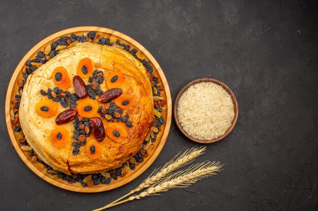 Vue de dessus du délicieux repas de riz shakh plov cuit à l'intérieur d'une pâte ronde avec des raisins secs sur la surface grise