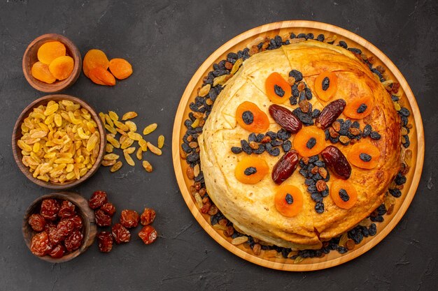 Vue de dessus du délicieux repas de riz shakh plov cuit à l'intérieur d'une pâte ronde avec des raisins secs sur la surface grise