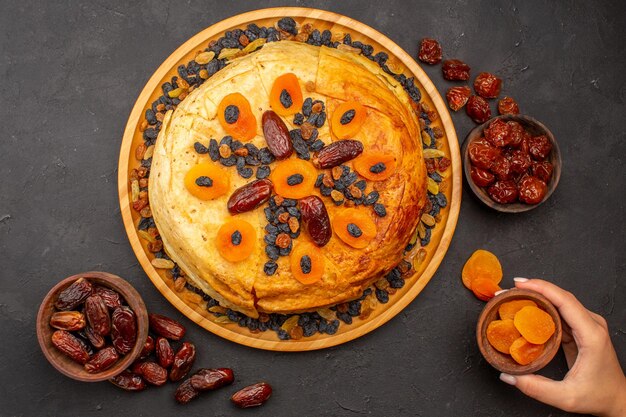 Vue de dessus du délicieux repas de riz shakh plov cuit à l'intérieur d'une pâte ronde avec des raisins secs sur la surface grise