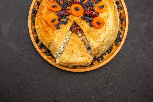 Vue de dessus du délicieux repas de riz shakh plov cuit à l'intérieur d'une pâte ronde avec des raisins secs sur la surface grise