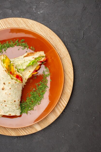 Vue de dessus du délicieux sandwich à la viande shaurma en tranches à l'intérieur de la plaque brune sur fond noir