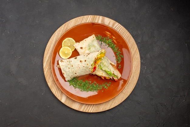 Vue de dessus du délicieux sandwich à la viande shaurma en tranches à l'intérieur de la plaque sur le noir