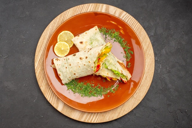 Vue de dessus du délicieux sandwich à la viande shaurma en tranches à l'intérieur de la plaque sur le noir