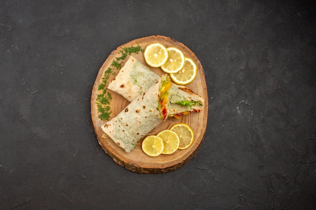 Vue de dessus du délicieux sandwich à la viande shaurma en tranches avec des tranches de citron sur fond noir