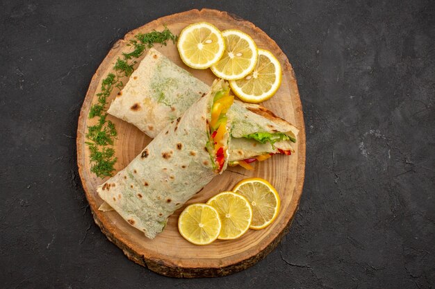 Vue de dessus du délicieux sandwich à la viande shaurma en tranches avec des tranches de citron sur fond noir