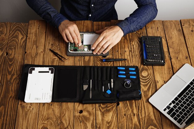 Vue de dessus du dispositif électronique propre professionnel sur table en bois dans son laboratoire près de ses outils avant de démonter