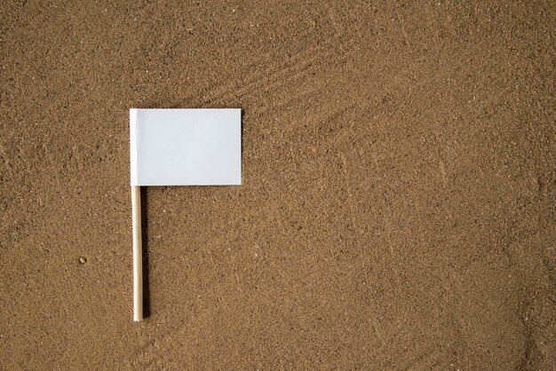 Vue de dessus du drapeau blanc sur le sable brun