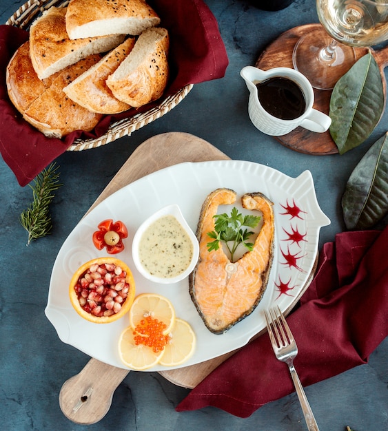 Vue de dessus du filet de saumon steak servi avec sauce aux herbes, grenades et citrons