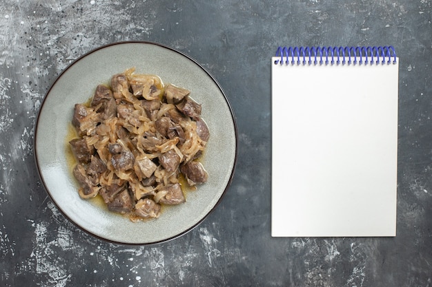 Vue De Dessus Du Foie Et De L'oignon Cuits Sur Une Assiette Ovale Et Un Cahier Vide