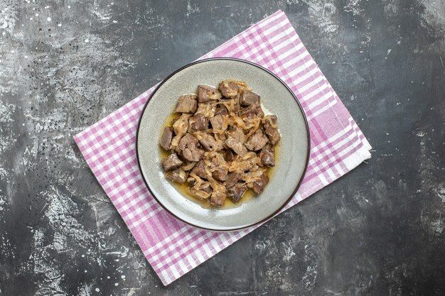 Vue de dessus du foie et de l'oignon cuits sur une assiette ovale sur un torchon