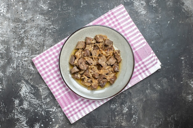 Vue de dessus du foie et de l'oignon cuits sur une assiette ovale sur un torchon