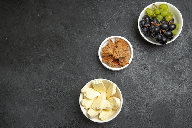 Vue de dessus du fromage blanc avec des raisins frais sur une surface sombre, des aliments aux fruits, du lait, du pain