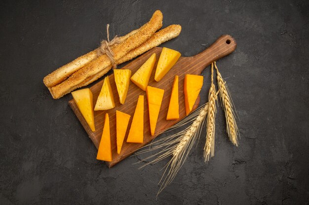 Vue de dessus du fromage frais tranché avec des petits pains sur fond sombre