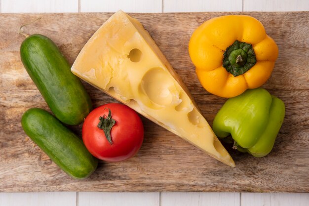 Vue de dessus du fromage maasdam avec concombres, tomates et poivrons sur un support