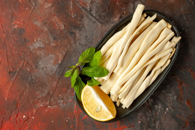 Vue de dessus du fromage en tranches avec un morceau de citron à l'intérieur de la plaque sur fond sombre