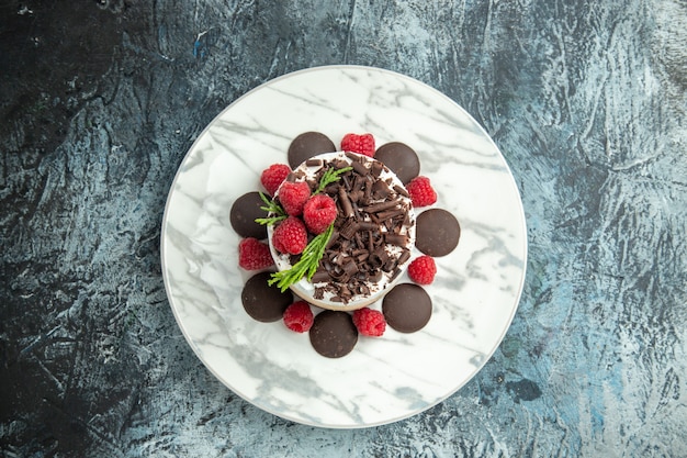 Vue de dessus du gâteau au fromage avec du chocolat sur une plaque ovale blanche sur l'espace libre de surface grise