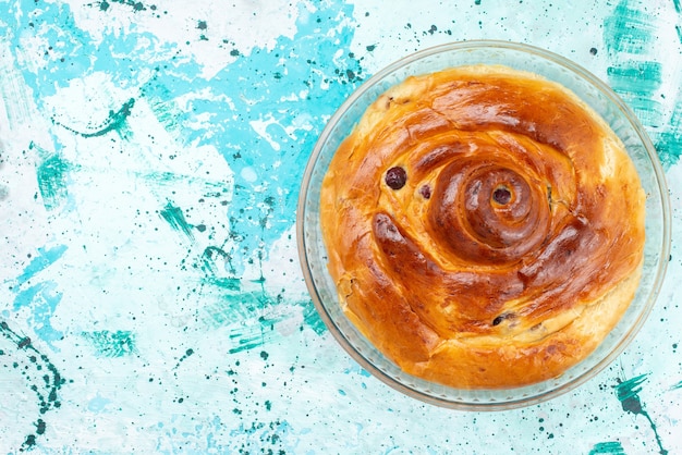 Vue de dessus du gâteau aux cerises entier avec des cerises à l'intérieur d'une casserole en verre sur bleu clair, gâteau cuire au four sucre sucré