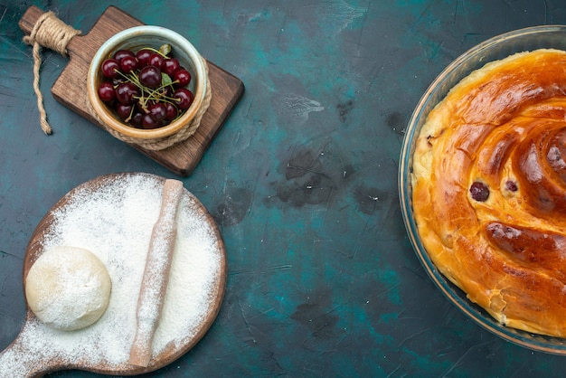 Photo gratuite vue de dessus du gâteau aux cerises avec de la farine de pâte et des cerises aigres sur noir, cuire le gâteau sucré aux fruits