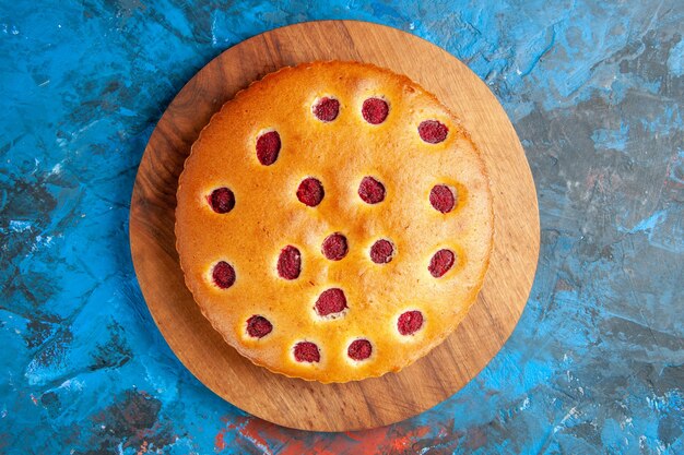 Vue de dessus du gâteau aux fraises sur planche de bois sur une surface bleue