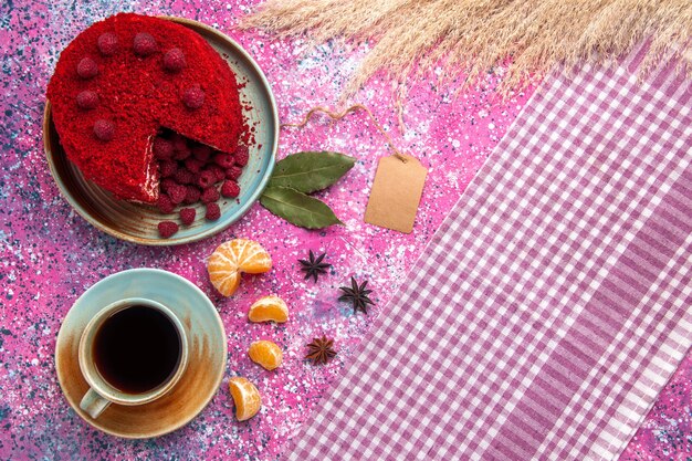 Vue de dessus du gâteau aux framboises rouges avec des mandarines et du thé sur la surface rose