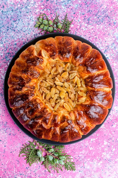 Photo gratuite vue de dessus du gâteau aux raisins secs gâteau à la tarte au four rond formé sur le bureau rose