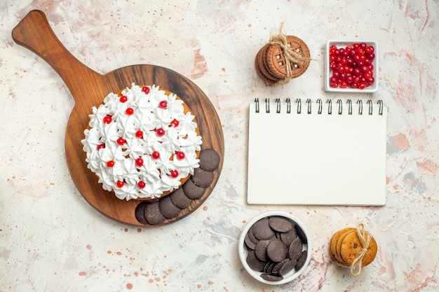 Vue de dessus du gâteau sur des bols pour ordinateur portable avec des baies et des biscuits au chocolat attachés avec une corde sur une table gris clair