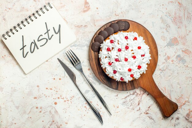 Photo gratuite vue de dessus du gâteau avec de la crème pâtissière blanche sur une planche à découper en bois