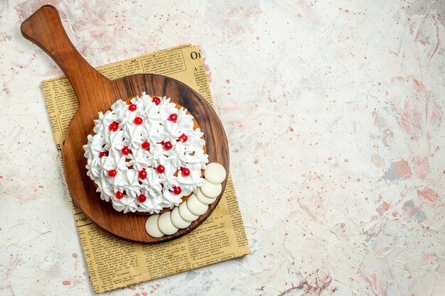 Vue de dessus du gâteau avec de la crème pâtissière blanche sur une planche à découper sur du papier journal