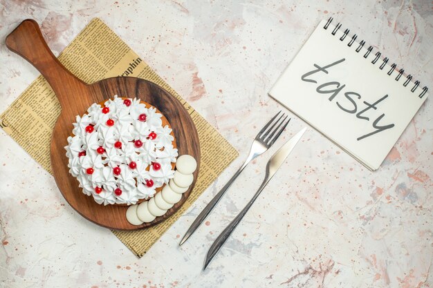 Vue de dessus du gâteau avec de la crème pâtissière blanche sur une planche à découper. savoureux écrit sur ordinateur portable