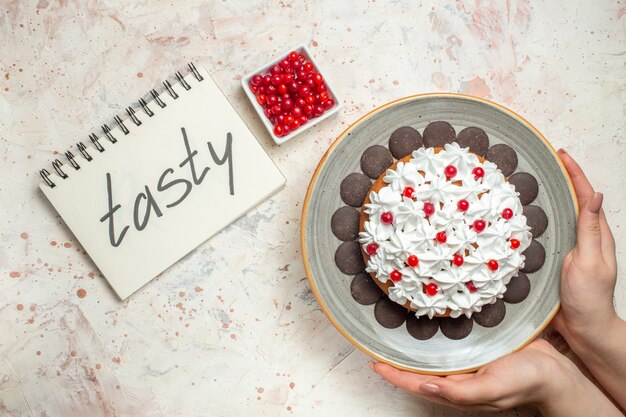 Vue de dessus du gâteau avec de la crème pâtissière et du chocolat dans une baie de main féminine dans un bol savoureux écrit sur un ordinateur portable